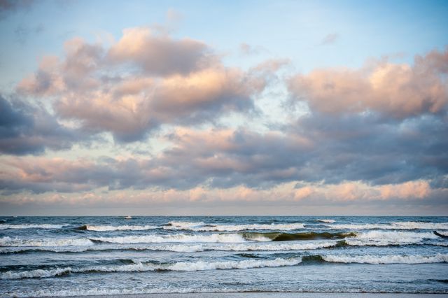 Gray-blue Baltic waves beneath peach and steel-coloured winter clouds.