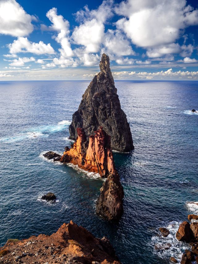 A sharp volcanic sea stack rising from clear Atlantic water off São Lourenço.