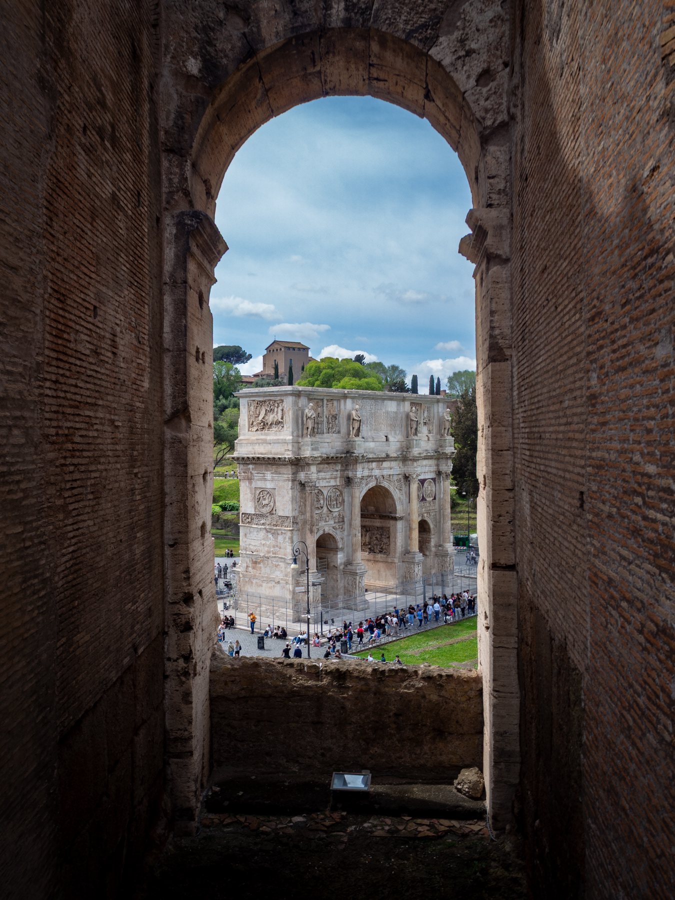 Roman ruins and a bright city view framed vertically through an ancient brick arch.