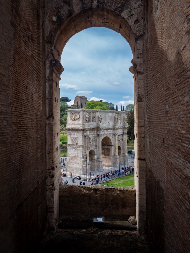 Roman ruins and a bright city view framed vertically through an ancient brick arch.