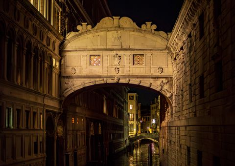 The enclosed Bridge of Sighs glowing above a narrow black canal between shadowed palaces.