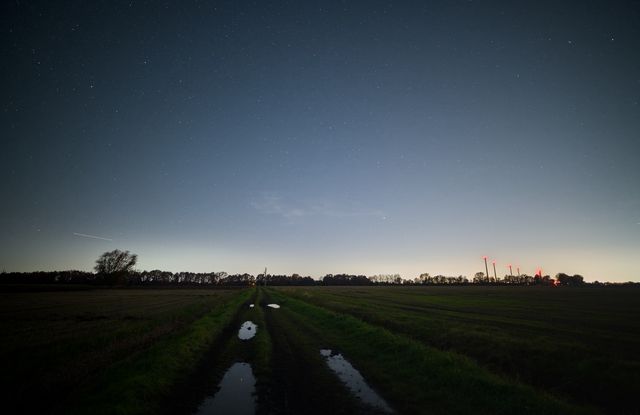A wet track crossing dark autumn fields beneath a faintly starred sky outside Gdańsk.