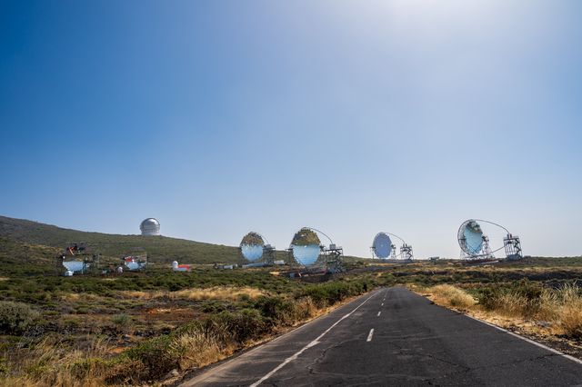 An empty mountain road approaching telescope domes and dishes at Roque de los Muchachos.