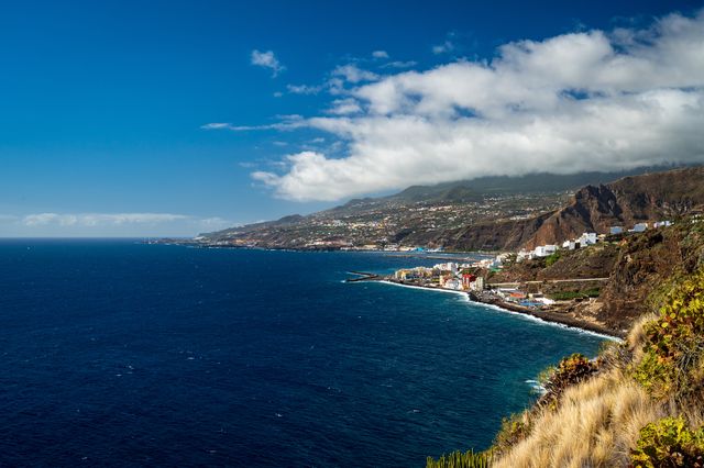 Wide Atlantic coastline with small settlements below cloud-covered mountains on La Palma.