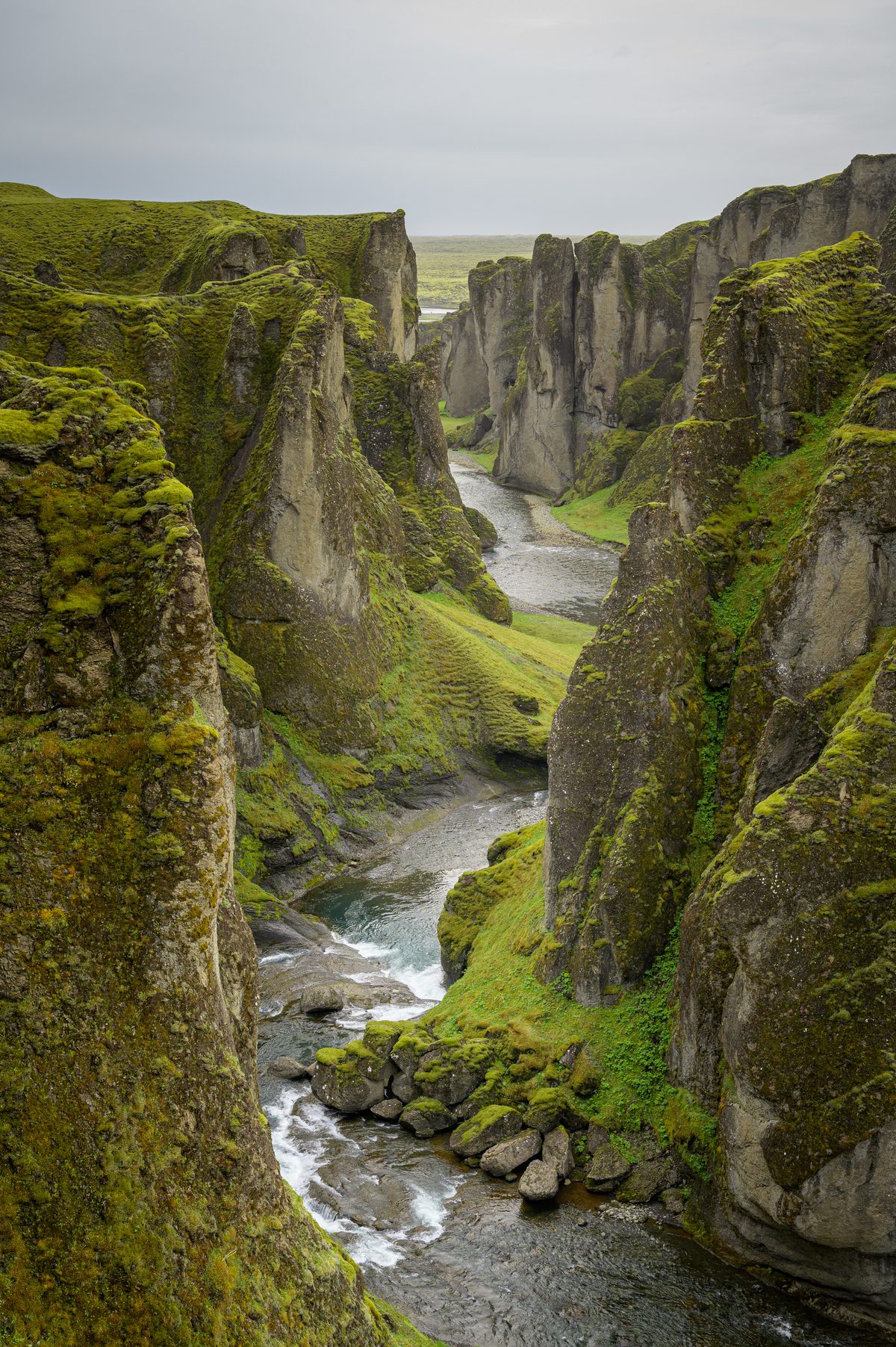 The Fjaðrá River winds between steep, moss-draped rock towers in the depths of Fjaðrárgljúfur canyon.