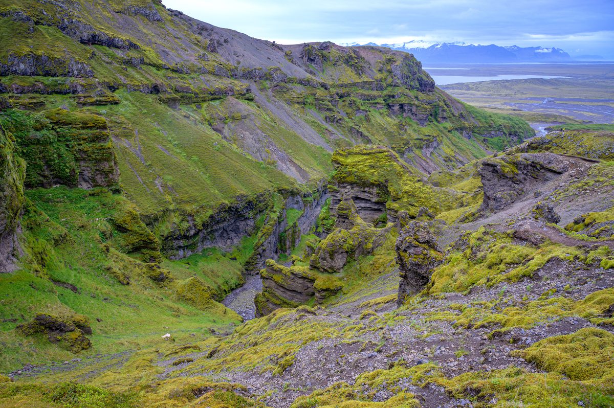 Steep green slopes and layered rock reveal the winding course of a river through Múlagljúfur.