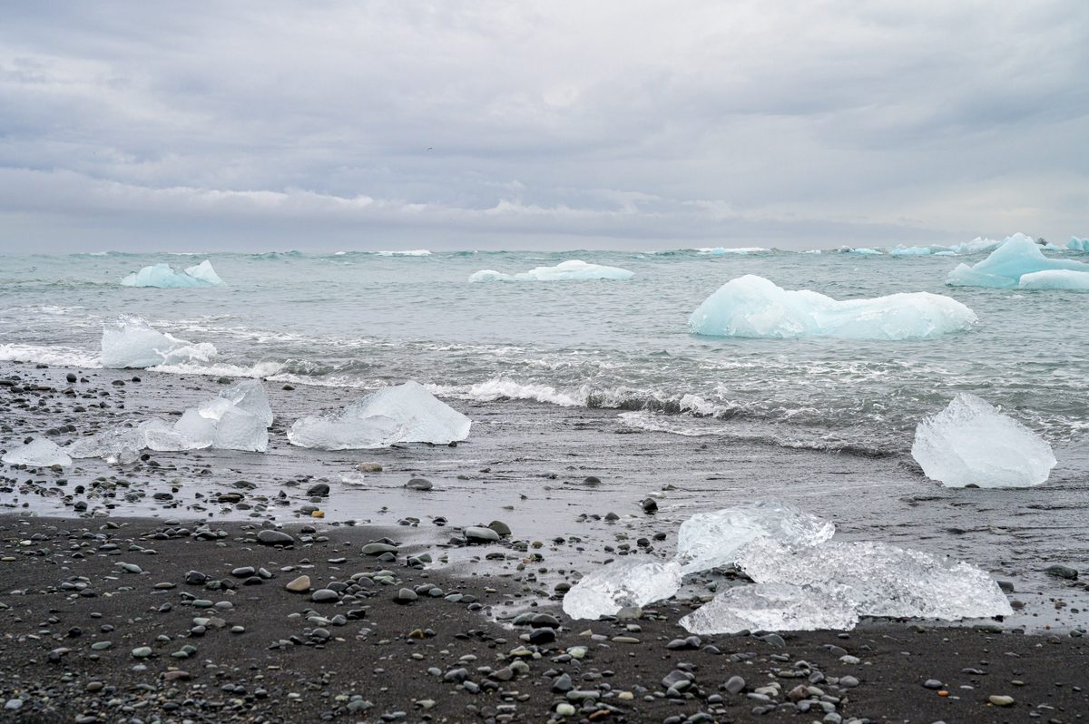 Clear and blue fragments of glacier ice lie across the dark volcanic shore of Diamond Beach.