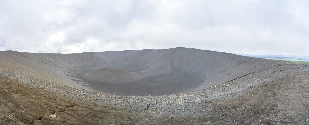 A wide panorama spans the immense gray inner bowl and smooth ash walls of Hverfjall beneath an overcast sky.